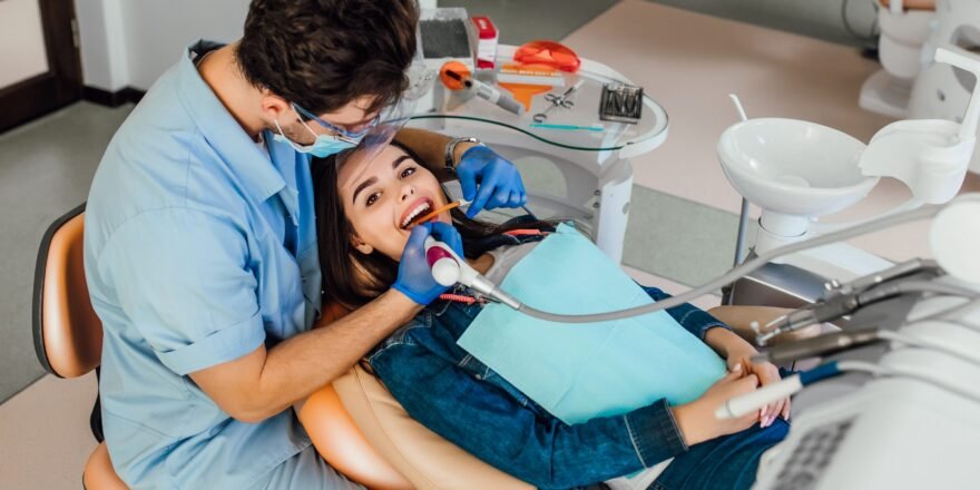 Young female patient with open mouth examining dental inspection at dentist office.